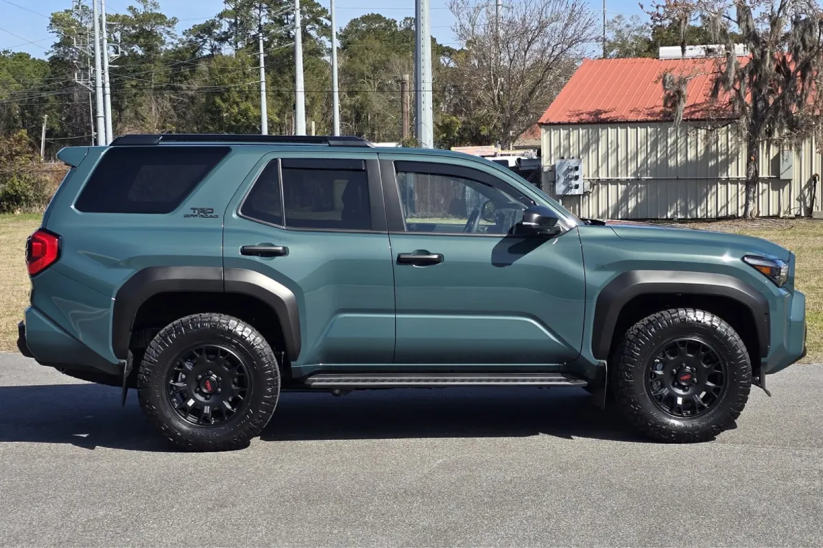 Green Toyota parked with black wheels and rugged tires.