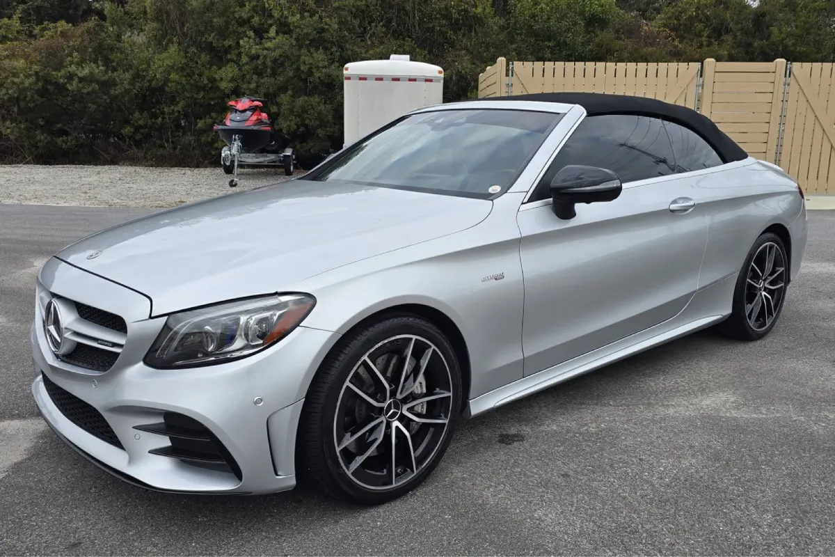 Silver Mercedes convertible with tinted windows and black rims in parking area