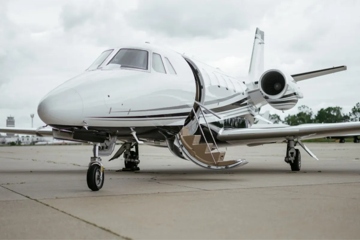White private jet parked on the runway with stairs open