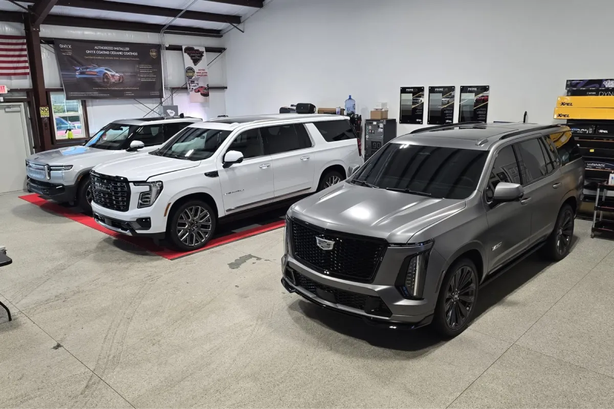SUVs with dark window tint inside a detailing shop.
