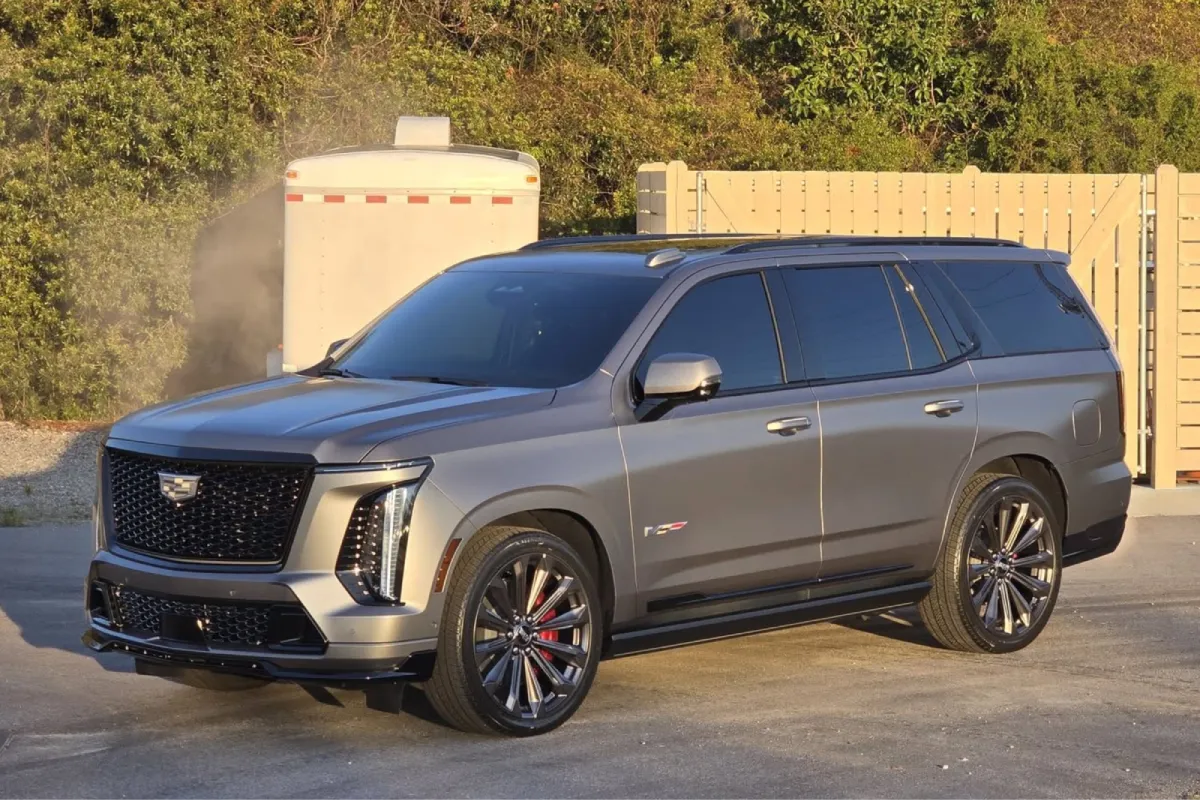Gray Cadillac Escalade with dark window tint parked outside.